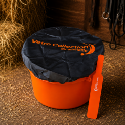 Orange waste bin with a black cover reading 'Vetro Collection by animallife' in a stable, with an orange scoop leaning against the side.
